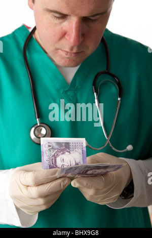 Mann trägt medizinische Peelings und Stethoskop 20 Pfund Sterling Banknoten zählen Stockfoto