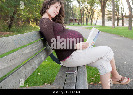 Schwangere Frau sitzend auf einem Park Bench, Manitoba, Kanada Stockfoto