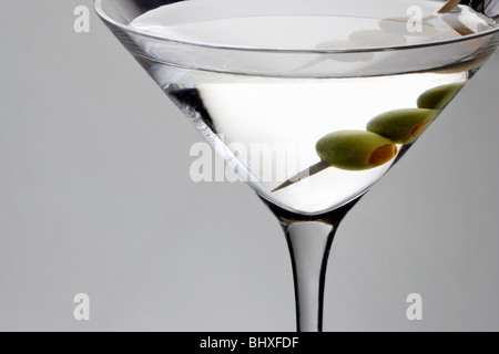 In der Nähe der Gerade nach oben Martini mit Oliven garnieren auf grauem Hintergrund Stockfoto