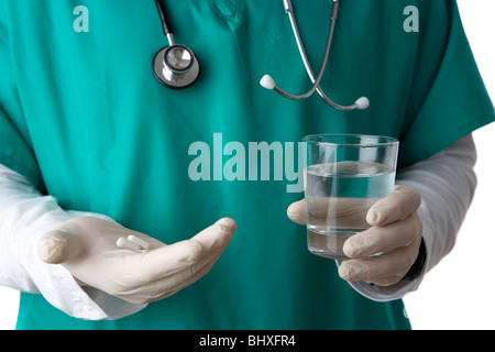 Mann trägt medizinische Peelings und Stethoskop mit Glas Wasser und Pillen Stockfoto