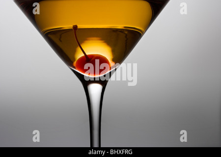 Manhattan oder Rob Roy cocktail mit Kirsche garnieren hautnah auf grauem Hintergrund Stockfoto