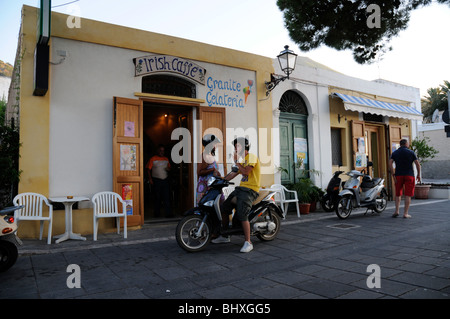 Ein italienisches Ehepaar auf einem Motorroller stoppen an einer gelateria in der Stadt Malfa Auf der äolischen Insel Salina, Sizilien, Italien. Stockfoto