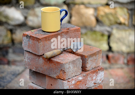 Ein Baumeister Becher Tee auf einem Stapel von aufgearbeiteten roten Ziegeln UK Stockfoto