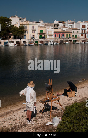 Ein Maler bei der Arbeit mit einem Modell im Hintergrund eines kleines Fischerdorfs Stockfoto