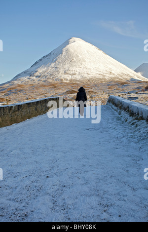 Eine Person, die zu Fuß über die Brücke Sligachan im Schnee, Isle Of Skye, Schottland Stockfoto