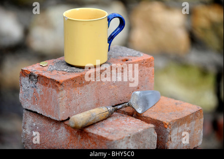 Ein Baumeister Becher Tee auf einem Stapel von aufgearbeiteten roten Ziegeln UK Stockfoto