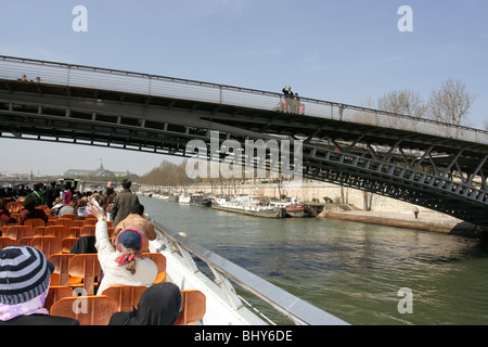 Fußgänger auf einer Brücke winkt Touristen auf eine Sightseeing Tour Boot am Fluss Seine in Paris, Frankreich. Stockfoto