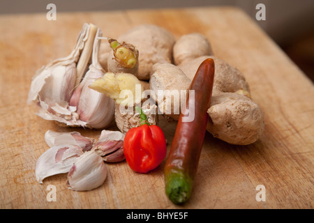 Gewürze zum Kochen, Knoblauch Chilis scotch Bonnet Ingwer auf ein Schneidbrett aus Holz Stockfoto