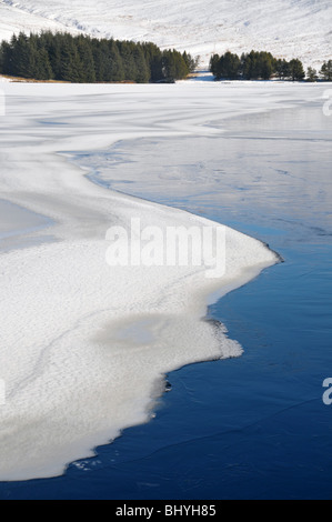 Zusammenfassung der Rückstau Reservoir, mit Eis und Schnee auf dem Wasser mit Tannen auf den fernen Rand des Wassers. Stockfoto