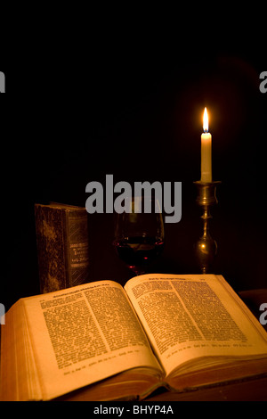 alte offene Buch, Glas Rotwein und eine Kerze Stockfoto