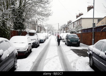 Eine Frau, die zu Fuß zur Arbeit im Schnee auf Schnee bedeckt Straße in Hounslow, westlich von London, im Winter 2009/10. Stockfoto