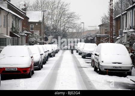 Eine Frau, die zu Fuß zur Arbeit im Schnee auf Schnee bedeckt Straße in Hounslow, westlich von London, im Winter 2009/10. Stockfoto