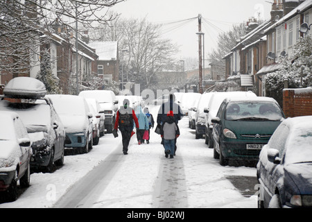 Eine Familie, die zu Fuß zur Schule, eine Schnee bedeckt Straße in Hounslow, westlich von London, im Winter 2009/10. Stockfoto