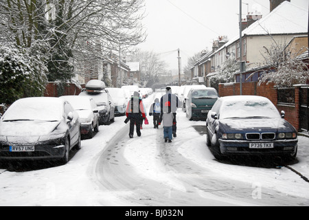 Eine Familie, die zu Fuß zur Schule, eine Schnee bedeckt Straße in Hounslow, westlich von London, im Winter 2009/10. Stockfoto