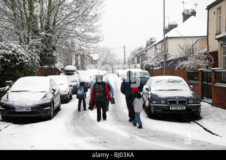 Eine Familie, die zu Fuß zur Schule, eine Schnee bedeckt Straße in Hounslow, westlich von London, im Winter 2009/10. Stockfoto