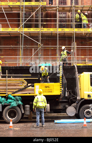 Gerüstbauer Arbeiter errichten Gerüst an einem Gebäude in London tragen Schutzhelme und Hi Viz Jacken Stockfoto