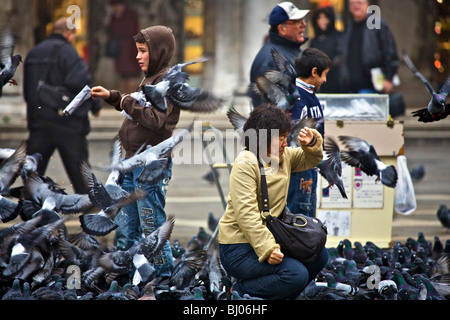 Touristen, die Glaubensbekennenden eines Schwarm Tauben auf der Piazza San Marco in Venedig, Veneto, Italien Stockfoto