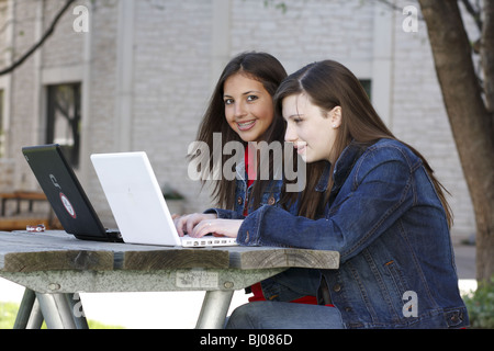 Zwei Teenager-Mädchen mit Notebooks an einem Picknicktisch Stockfoto
