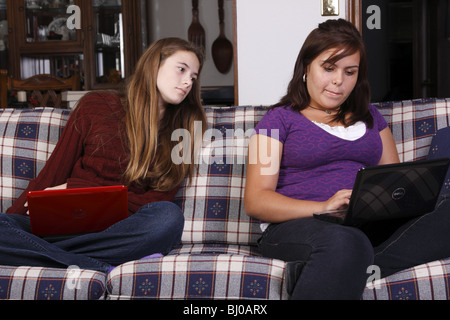 Ein Teenager-Mädchen auf der Suche über Schulter ihre Freunde um Bildschirm zu sehen Stockfoto