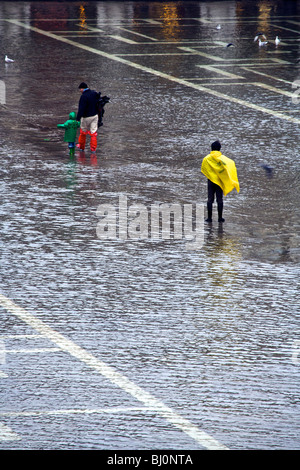 Eine Familie waten durch die überfluteten Piazza San Marco in Venedig, Veneto, Italien Stockfoto