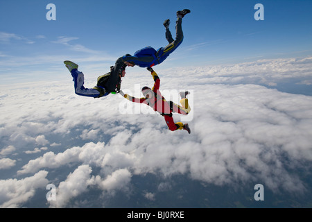 Skydive Freefly Team bildet eine spezielle HYBRID-Formation über eine spektakuläre cloud-Landschaft in den Himmel mit 130 km/h. Stockfoto