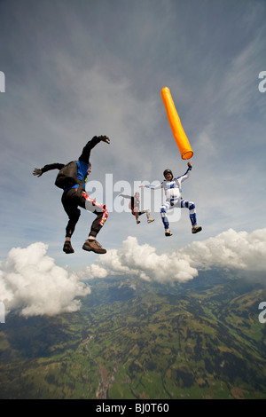 Fallschirmspringer Kopf fliegen liegen ein Team und orange Luftschlauch über eine spektakuläre Berg- und Cloud-Landschaft zu halten. Stockfoto