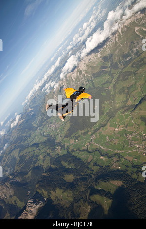 Skydiver fliegt innerhalb seiner gelb / schwarz Wingsuit über eine spektakuläre Landschaft. Der Taucher ist die Verfolgung entlang der Berge. Stockfoto