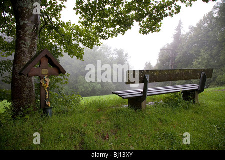 Sitzbank und ein Kreuz in der Nähe eines Waldes, Ehrwald, Österreich Stockfoto