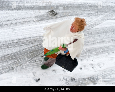 Frau mit Regenschirm gehen auf Schnee bedeckt Straße - Frankreich. Stockfoto