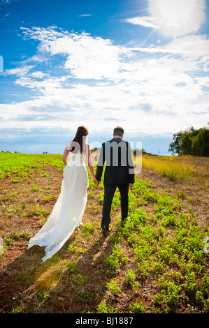 Braut und Bräutigam zusammen im Feld spazieren Stockfoto