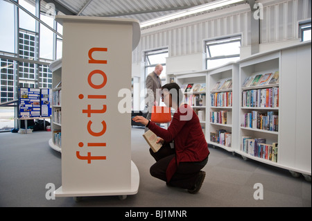 Hamworthy Bibliothek, Mitarbeiter kniet ein Buch im Regal wieder aufsetzen Stockfoto