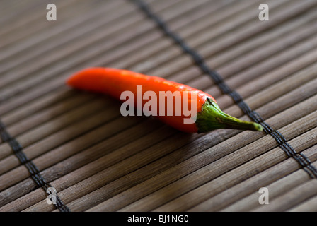 Eine einzelne rote Chilischote auf einem Bambus-Oberfläche Stockfoto