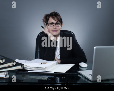 schöne fröhliche kaukasischen hören Blick in die Kamera sitzt am Schreibtisch auf Hintergrund isoliert Stockfoto