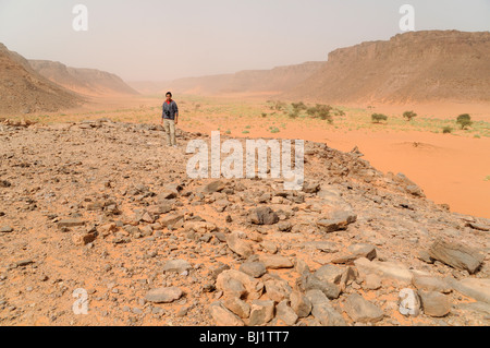 Ein junger ägyptischer Mann stand auf einem felsigen Plateau oberhalb von Wadi Hamra im gilf Kebir in der westlichen Wüste Ägyptens. Stockfoto