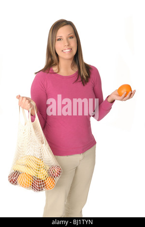 Attraktive junge Frau mit wiederverwendbaren Einkaufstasche Shopping gefüllt mit frischem Obst. Stockfoto