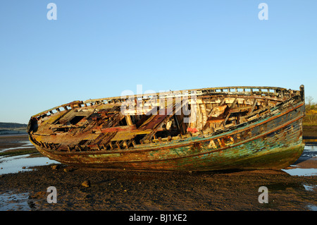 Die faulende Rumpf eines Fischerbootes Holz liegt am Strand. Stadt Dulas, Anglesey, UK. Stockfoto