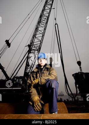 Kran-Fahrer tragen Schutzhelm posiert vor seinem Kran. Amsterdam Hafen, Noord Holland, Niederlande Stockfoto