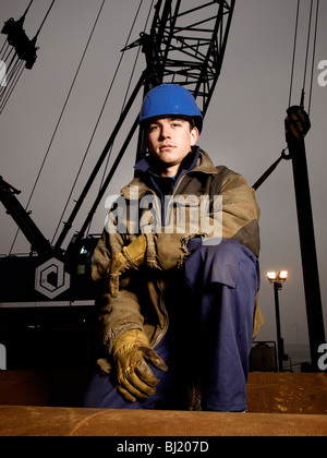 Kran-Fahrer tragen Schutzhelm posiert vor seinem Kran. Amsterdam Hafen, Noord Holland, Niederlande Stockfoto