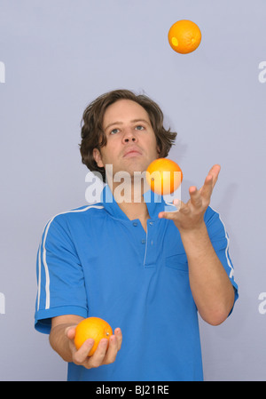 Junger attraktiver Mann Jonglieren mit Orangen oder multitasking Stockfoto