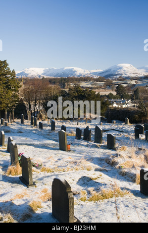 Grabsteine in Hawkshead Kirche Friedhof mit Schnee bedeckt Cumbrian Mountains Seenplatte Cumbria England Vereinigtes Königreich UK Stockfoto