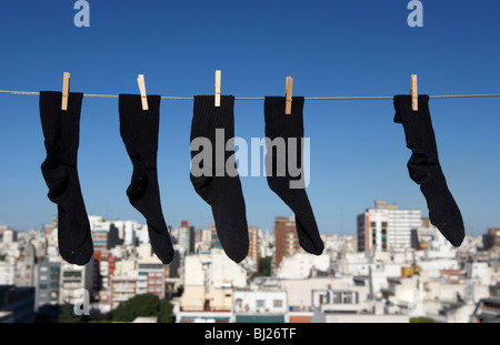 fünf zwei Paare und eine seltsame schwarze Socken hängen an einer Wäscheleine mit blauem Himmel über einer Stadt Skyine in Buenos Aires Argentinien Stockfoto