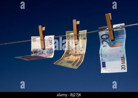 zwanzig Pfund-Dollar-Euro-Banknoten an eine Wäscheleine mit blauem Himmel hängen Stockfoto