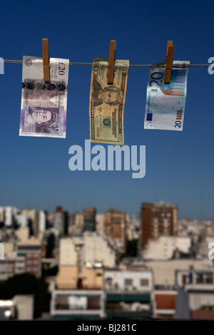 zwanzig Pfund-Dollar-Euro-Banknoten hängt eine Wäscheleine mit blauem Himmel über der Skyline der Stadt Stockfoto