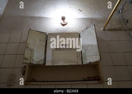 alten gespiegelten Badezimmerschrank in einem heruntergekommenen Badezimmer Stockfoto