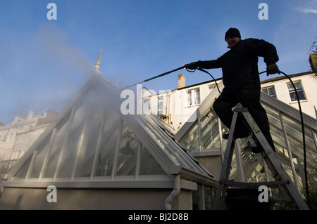 Ein Mann macht Waschen ein Gewächshaus mit einem Jet-Spray. Stockfoto