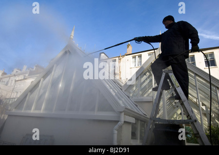 Ein Mann macht Waschen ein Gewächshaus mit einem Jet-Spray. Stockfoto