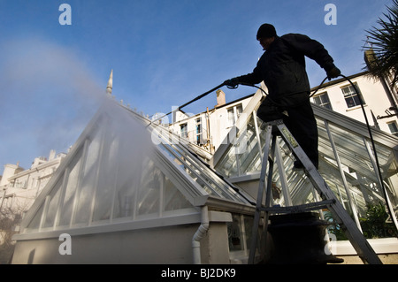 Ein Mann macht Waschen ein Gewächshaus mit einem Jet-Spray. Stockfoto