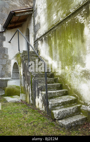Wasserflecken, mineralische Ablagerungen und Formen färben diese alte Granit und Beton Treppe und Wand in eine verlassene Militäranlage. Stockfoto