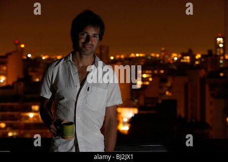 Spanisch Latein-Mann auf Dach mit einer Tasse Kaffee am Abend Stadt in den Hintergrund-Buenos Aires-Argentinien Stockfoto