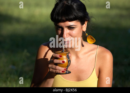 junge spanische Latin Frau trinken Yerba Mate aus einem Kürbis in den Park in Buenos Aires Argentinien Stockfoto